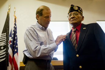 Perry Benally receives a Silver Star from Senator Tom Udall in a ceremony at City Hall in Gallup on Friday. Benally received the Silver Star more than 40 years after a combat action during the Vietnam War in 1967. Benally was mortally wounded and, in spite of running out of ammunition and hand to hand combat with North Vietnamese Army soldiers, Benally survived to be rescued a day later - on his 22nd birthday. © 2011 Gallup Independent / Adron Gardner 